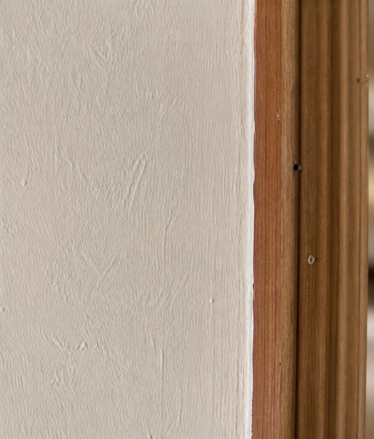 Detailaufnahme einer frisch gestrichenen Innenwand mit sauberer Kante am Holzrahmen